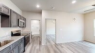 This well-appointed one-bedroom, one-bathroom unit at 3305 Flynn Rd in Dothan, Alabama, offers a thoughtfully designed single-floor layout that maximizes every inch of its compact footprint. Light wood-style luxury vinyl plank flooring runs seamlessly throughout, lending a clean, cohesive look to the entire space.

The kitchen is a standout feature, showcasing dark gray shaker-style cabinetry, granite-look countertops, and a full suite of stainless steel appliances including a refrigerator, electric range, and over-the-range microwave. Recessed lighting keeps the space bright and functional.

The open living area connects naturally to the kitchen and entry, creating an easy flow. The front entry features a ceiling fan with light fixture and a window that brings in natural light and outdoor views.

The bedroom is a comfortable size, equipped with a wall-mounted mini-split HVAC unit, a ceiling fan, a window with blinds for natural light, and access to a walk-in closet with built-in shelving for ample storage.

The bathroom is clean and modern, featuring a granite-top vanity with a dark wood cabinet, a full tub-shower combo with brushed nickel fixtures, and matching flooring. The neutral color palette throughout creates a bright, welcoming ambiance ideal for comfortable everyday living.