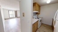 This 2-bedroom, 1-bathroom unit in Calgary, AB offers a practical and comfortable layout across a single floor. Light-toned hardwood flooring runs throughout the unit, creating a cohesive and clean aesthetic in every room.

The living room is an open, well-lit space anchored by a large window with balcony access, allowing natural light to fill the room. A pass-through opening connects the living area to the kitchen, maintaining an open feel between the two spaces. The kitchen features a galley-style layout with warm wood cabinetry on both sides, light countertops, a double stainless steel sink, and a white electric range with overhead cabinetry for ample storage.

The primary bedroom is generously sized, offering a large window with outdoor views and a sliding-door closet with a full-width hanging rod. The second bedroom is comparably bright, also featuring a large window and baseboard heating. Both bedrooms are finished with the same light hardwood flooring and textured ceilings found throughout the unit.

The bathroom includes a wood-toned vanity with a single sink, a wall-mounted mirror with overhead lighting, a tiled shower, and light hardwood flooring. The unit also features baseboard heating throughout, a textured ceiling finish, and an intercom panel near the kitchen entry.