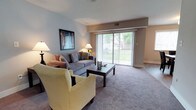Located at 41 Winterhaven Dr in Newark, Delaware, this single-floor residence offers a well-appointed and inviting living environment. The living room serves as the heart of the home, featuring plush wall-to-wall carpeting and a neutral color palette that creates a warm, welcoming atmosphere. Large sliding glass doors span the width of the room, flooding the space with abundant natural light and providing direct views of the surrounding greenery outdoors. The seamless indoor-outdoor connection gives the living area an open, airy feel. The room comfortably accommodates a full seating arrangement, with ample space for both relaxing and entertaining. Soft, neutral-toned walls complement the carpeted flooring, while recessed ceiling details add subtle architectural interest. The overall design emphasizes comfort and functionality, with a layout that flows naturally throughout the single level. This home's single-floor layout offers convenient, accessible living, making it a practical and pleasant space for everyday life in the Newark, Delaware community.