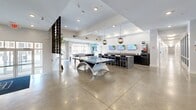 This expansive 11,020 square foot facility in Columbia, SC, offers a blend of modern amenities and functional spaces. The single-story structure boasts 21 distinct areas, each serving a unique purpose. Upon entry, visitors are greeted by a sleek lobby with polished concrete floors, recessed lighting, and a striking wooden partition that adds warmth to the contemporary design.

The property features a well-equipped fitness center with state-of-the-art cardio and strength training equipment. Large windows allow natural light to flood the vibrant blue-walled space, creating an energizing atmosphere for workouts. Adjacent, a multi-purpose room with orange walls and hardwood flooring offers versatility for group activities or classes.

Outdoor amenities include a spacious swimming pool surrounded by lounge chairs and umbrellas, perfect for relaxation and recreation. The building's exterior showcases a mix of light and dark siding, creating visual interest and modern curb appeal.

Inside, the facility houses various functional spaces including a game room with vending machines, a business center, and well-maintained restroom facilities. The interior design throughout emphasizes clean lines, neutral color palettes, and ample lighting, fostering a welcoming and efficient environment.

This multi-purpose facility seamlessly combines work, leisure, and living spaces, catering to diverse needs and preferences in a single, thoughtfully designed location.