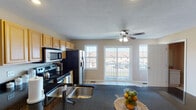 This well-designed multi-story home spans three floors and offers a thoughtfully laid-out living experience. The heart of the home is an open-concept main level where the kitchen flows seamlessly into the living area. The kitchen is outfitted with dark granite countertops, light maple cabinetry, stainless steel appliances including a range, microwave, and refrigerator, and a double-basin sink. Tile flooring grounds the kitchen space, which opens into a carpeted living area featuring a ceiling fan and direct access to a private balcony through glass patio doors, flooding the space with natural light and offering views of the surrounding neighborhood.

A staircase connects the floors, leading to the upper levels where the bedrooms are located. Each bedroom features plush carpet, a ceiling fan with light fixture, and windows with blinds that allow for natural light. The primary bathroom is generously sized with a double-sink vanity, marble-look countertops, warm wood cabinetry, tile flooring, and a shower-tub combination. A secondary bathroom mirrors this clean aesthetic with a single-sink vanity and tile floors. A dedicated laundry room with tile flooring and utility hookups completes the functional layout of this comfortable, move-in ready home.