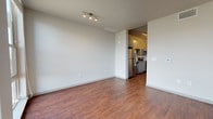 Located at 380 W 13th Ave in Denver's vibrant Golden Triangle Creative District, this contemporary single-floor residence combines modern finishes with a clean, open aesthetic. Rich hardwood-style flooring flows throughout the unit, anchoring each space with warmth and continuity.

The open living area is bright and versatile, illuminated by track lighting and a ceiling fan. Floor-to-ceiling windows in the main living space flood the room with natural light while offering sweeping views of the Denver skyline, creating a striking urban backdrop.

The kitchen is well-appointed with gray flat-front cabinetry, granite countertops, a classic subway tile backsplash, and a full suite of stainless steel appliances including a refrigerator, range, microwave, and dishwasher. The layout is functional and efficient, connecting seamlessly to the living area.

The bathroom features a tub-shower combination with white subway tile surround, a vanity with granite countertop and framed mirror, taupe cabinetry for storage, and consistent hardwood-style flooring that ties the space together. Clean white walls throughout the unit create a neutral, move-in-ready canvas with a fresh, modern ambiance.