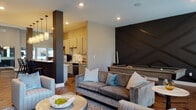 Located at 3785 Codet Rd. in Columbus, Ohio, this thoughtfully designed single-floor clubhouse offers a sophisticated blend of comfort and functionality. The open-concept layout is anchored by rich herringbone-patterned hardwood flooring that flows seamlessly throughout the entire space, creating a warm and cohesive aesthetic.

The central lounge area serves as the heart of the space, featuring a dramatic floor-to-ceiling dark tile fireplace surround that commands attention. Multiple seating arrangements, abundant natural light from large windows with transom accents, and a wall-mounted television make this an inviting gathering space. Recessed lighting complements the natural light throughout.

Adjacent to the lounge is a recreation zone with a full-size billiards table set against a striking geometric dark feature wall, adding a bold design element. The fully equipped kitchen boasts gray shaker-style cabinetry, white subway tile backsplash, bright white countertops, and a generous island illuminated by a row of pendant lights — ideal for entertaining.

A dedicated workstation nook provides two computer stations set against a textured wall panel backdrop, complete with pendant lighting, offering a practical and quiet workspace. A glass-paneled room is also visible, adding a modern architectural touch. The overall ambiance is contemporary and upscale, designed to serve as a premier community amenity.