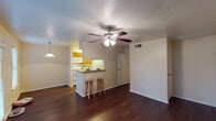 This one-bedroom, one-bathroom unit in Huntsville, Texas offers a well-designed single-floor layout that maximizes functionality and comfort. The living area is open and inviting, featuring rich dark hardwood-style flooring, a ceiling fan with integrated lighting, and a door leading to an outdoor area with natural light filtering through slatted blinds. A peninsula-style breakfast bar with bar stool seating connects the living space to the kitchen, creating an easy flow for everyday living and entertaining.

The galley kitchen is thoughtfully arranged with warm wood cabinetry lining both walls, light countertops, white appliances including a range, microwave, and refrigerator, and a double-basin sink. The efficient corridor layout makes the most of the available space while keeping essentials within easy reach.

The bedroom is carpeted for warmth and comfort, featuring a ceiling fan, a window for natural light, and a closet. The bathroom includes a wood-toned vanity with ample counter space, a large wall mirror with overhead lighting, and a separate water closet area. Throughout the unit, neutral wall tones and consistent finishes create a cohesive and practical living environment well-suited for comfortable, everyday use.