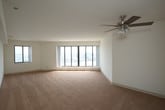Located at 1 Harbor Ct in Portsmouth, Virginia, this single-floor residence offers an impressive combination of waterfront views and functional living spaces. The layout is anchored by a generously sized living area featuring warm carpeted flooring, crisp white walls, and a ceiling fan with light fixture. Floor-to-ceiling panoramic windows frame breathtaking views of the harbor and the Norfolk skyline, flooding the space with abundant natural light throughout the day.

The kitchen is thoughtfully designed with white cabinetry offering ample storage, granite-style countertops, tile flooring, and a full suite of white appliances including a range with oven, built-in microwave, and dishwasher. A stainless steel sink completes the functional workspace.

The bedroom continues the waterfront theme, featuring the same large multi-panel windows that capture sweeping harbor vistas. Soft carpeting and clean white walls create a calm, restful atmosphere. A hallway leads to a well-organized walk-in closet with built-in shelving, providing excellent storage capacity. The bathroom is finished with white tile flooring and includes a full soaking tub with tub-surround and brushed nickel fixtures. This residence delivers a serene, light-filled environment with remarkable water views at every turn.
