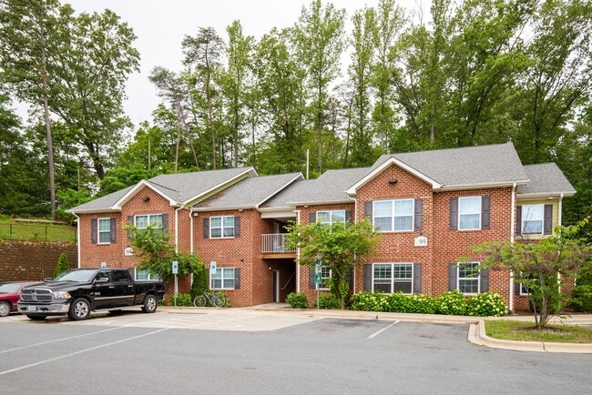 Charming red brick apartment homes surrounded by lush greenery—where peaceful living meets thoughtful design. - Timberland Park