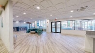 Located at 243 Main St in Hartford, Connecticut, this single-floor commercial space offers a generously sized, open-plan layout with a clean, contemporary design throughout. Light wood-look luxury vinyl flooring runs continuously across the entire floor, lending warmth and cohesion to the space.

Upon entry, large floor-to-ceiling windows and a glass door welcome abundant natural light and provide clear views of the bustling downtown Hartford streetscape. A stylish reception desk and adjacent seating area create a polished front-of-house experience, ideal for welcoming clients or guests.

The space transitions into a well-appointed lounge area, featuring teal upholstered seating, decorative wall art, a wall-mounted flat-screen television, and a textured accent wall that adds visual depth and character. The sophisticated color palette of white, teal, and silver carries a cohesive, branded aesthetic throughout.

A fully enclosed glass-walled fitness room — branded "Element" — provides a dedicated workout area equipped with exercise benches and free weights, all visible through the transparent partition walls, maintaining an open and airy feel without compromising functionality.

The coffered drop ceiling with recessed LED lighting is consistent throughout, providing bright, even illumination across every zone. The layout also includes a glass-partitioned conference or meeting area, rounding out this versatile and professionally designed commercial space.