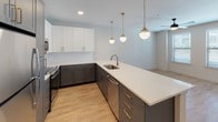 Located in Dallas's vibrant 75208 zip code, this two-story residence at 612 N Zang Blvd combines contemporary design with functional living across two well-appointed levels. The open-concept kitchen serves as a central highlight, featuring two-tone cabinetry with charcoal lower cabinets and crisp white uppers, a white quartz countertop island with an undermount sink, brass-finish hardware and faucets, a classic subway tile backsplash, and stainless steel appliances. Three globe pendant lights with gold fixtures hang above the island, adding a refined, modern touch. The living area connects seamlessly to the kitchen and features warm wood-look flooring and a built-in recessed shelving unit that provides both storage and display space. The bedroom is carpeted for comfort, includes a ceiling fan, and benefits from a large window that invites natural light and exterior views. Bathrooms throughout the home are finished with penny-tile flooring, gray cabinetry with gold hardware, white quartz vanity tops, black matte fixtures, and subway tile shower surrounds. The primary bathroom includes access to a walk-in closet. A staircase connects both floors, creating a cohesive and thoughtfully designed multi-level living space.