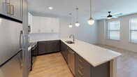 Located in Dallas's vibrant 75208 zip code, this two-story residence at 612 N Zang Blvd combines contemporary design with functional living across two well-appointed levels. The open-concept kitchen serves as a central highlight, featuring two-tone cabinetry with charcoal lower cabinets and crisp white uppers, a white quartz countertop island with an undermount sink, brass-finish hardware and faucets, a classic subway tile backsplash, and stainless steel appliances. Three globe pendant lights with gold fixtures hang above the island, adding a refined, modern touch. The living area connects seamlessly to the kitchen and features warm wood-look flooring and a built-in recessed shelving unit that provides both storage and display space. The bedroom is carpeted for comfort, includes a ceiling fan, and benefits from a large window that invites natural light and exterior views. Bathrooms throughout the home are finished with penny-tile flooring, gray cabinetry with gold hardware, white quartz vanity tops, black matte fixtures, and subway tile shower surrounds. The primary bathroom includes access to a walk-in closet. A staircase connects both floors, creating a cohesive and thoughtfully designed multi-level living space.