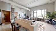 Located at 201 N Mead St in the heart of downtown Wichita, this 2-bedroom, 1-bathroom loft blends industrial character with comfortable urban living. The open-concept living and kitchen area is immediately striking, featuring whitewashed wood plank ceilings with exposed structural beams and large ductwork that pays homage to the building's industrial origins. Oversized factory-style windows flood the space with natural light and offer sweeping views of the cityscape, creating an airy, expansive atmosphere.

The kitchen features warm wood cabinetry, granite-style countertops, and wood-look flooring, flowing seamlessly into the living and dining areas. The dining nook sits directly beside the large windows, making it an inviting spot with abundant natural light. The living area is generously proportioned, complete with a media console housing a built-in electric fireplace.

The spacious primary bedroom offers soaring ceilings with a ceiling fan, plush carpeting, and ample natural light filtered through vertical blinds. The second bedroom is cozy, featuring sliding wood closet doors and sheer window treatments. The bathroom is well-appointed with wood cabinetry, granite countertops, and a tub-shower combination. A dedicated in-unit laundry room adds everyday convenience to this distinctive downtown loft.