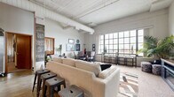 Located at 201 N Mead St in the heart of downtown Wichita, this 2-bedroom, 1-bathroom loft blends industrial character with comfortable urban living. The open-concept living and kitchen area is immediately striking, featuring whitewashed wood plank ceilings with exposed structural beams and large ductwork that pays homage to the building's industrial origins. Oversized factory-style windows flood the space with natural light and offer sweeping views of the cityscape, creating an airy, expansive atmosphere.

The kitchen features warm wood cabinetry, granite-style countertops, and wood-look flooring, flowing seamlessly into the living and dining areas. The dining nook sits directly beside the large windows, making it an inviting spot with abundant natural light. The living area is generously proportioned, complete with a media console housing a built-in electric fireplace.

The spacious primary bedroom offers soaring ceilings with a ceiling fan, plush carpeting, and ample natural light filtered through vertical blinds. The second bedroom is cozy, featuring sliding wood closet doors and sheer window treatments. The bathroom is well-appointed with wood cabinetry, granite countertops, and a tub-shower combination. A dedicated in-unit laundry room adds everyday convenience to this distinctive downtown loft.