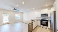 This two-story home offers a thoughtfully laid-out floor plan across two levels, combining functional design with clean, modern finishes. The ground floor hosts an open-concept kitchen and living area, where crisp white cabinetry, granite-style countertops, and a full suite of stainless steel appliances — including a range, microwave, dishwasher, and refrigerator — come together in a bright, welcoming space. Recessed lighting and a ceiling fan add comfort, while light hardwood-style flooring flows throughout, complementing the neutral wall tones. A single-car garage with an automatic door and electrical panel access is also found on this level.

The upper floor contains all three bedrooms, including a spacious primary bedroom with a dedicated walk-in closet fitted with wire shelving. Additional bedrooms feature double-door closets and windows that bring in natural light. All three bathrooms are finished consistently with granite-style vanity tops, white cabinetry, and tub-shower combinations. A hallway and staircase connect the two levels seamlessly.

Throughout the home, light wood-look flooring, white panel doors, and a cohesive neutral palette create a clean, modern ambiance that is both practical and inviting.