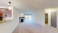 Located in Menomonee Falls, Wisconsin, this single-floor, 2-bedroom, 2-bathroom home offers a thoughtfully designed layout that balances comfort and functionality. The open-concept living area is generously sized, with plush carpeting, recessed lighting, and a tile-surround fireplace with a dark wood mantle as a focal point. Sliding glass doors flood the space with natural light and provide direct views of the surrounding greenery outdoors. The kitchen is well-equipped with rich, warm-toned cabinetry, a granite-topped peninsula with pendant lighting, stainless steel appliances including a French door refrigerator and electric range with microwave, and durable hardwood-style flooring. The spacious primary bedroom features soft carpeting and ample room to accommodate a full suite of furnishings, while the second bedroom benefits from a large window overlooking the landscaped exterior. Both bathrooms are finished with tile flooring, vanities with white countertops, and sleek matte black hardware accents. A dedicated laundry room with overhead shelving and tile flooring adds practical convenience. Clean neutral tones and consistent finishes throughout the home create a cohesive, move-in-ready atmosphere.