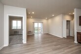Located at 1765 SE Glacier Trail in Waukee, Iowa, this single-floor, four-bedroom, two-bathroom residence offers a well-organized and functional layout. The open-concept kitchen and living area serves as the heart of the home, featuring rich dark wood cabinetry, white countertops, and a full suite of stainless steel appliances including a refrigerator, range, microwave, and dishwasher. Light wood-tone flooring runs throughout the main living spaces, lending a clean, modern aesthetic. Sliding glass doors lead from the living area to a private balcony, allowing natural light to fill the space while offering open views of the surrounding landscape. The bedrooms are comfortably sized, with plush carpeting and large windows that invite in additional natural light and scenic outdoor views. The primary bedroom provides a private retreat with ample space. Two full bathrooms are well-appointed with dark wood vanities, white countertops, and brushed nickel fixtures; one features a walk-in shower and the other a full tub/shower combo. A dedicated laundry area, utility room, and an impressive eight closets throughout the unit ensure generous storage. A central hallway connects all rooms efficiently, completing this thoughtfully designed home.