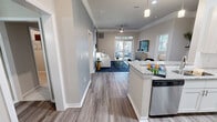Located at 3100 West Ashley in Charleston, South Carolina, this single-floor residence is designed with a contemporary open-concept layout that seamlessly connects the kitchen, dining, and living areas. The kitchen features granite countertops, stainless steel appliances, and a pendant-lit island that transitions naturally into the dining space, which is accented by crown molding and wood-look flooring throughout.

The living room is bright and inviting, with a ceiling fan, crown molding, and a sliding glass door that opens directly onto a private balcony with outdoor seating. A blue accent wall adds visual depth, complementing the neutral tones found throughout the unit.

The bedroom is a calm retreat with a large window allowing natural light, plush carpeting, and a teal accent wall. An adjoining bathroom offers a combination tub and shower with brushed gold fixtures, a white vanity with ample storage, and a walk-in closet. A second bathroom features an extended white vanity with a wide mirror and modern multi-bulb lighting. The space balances modern finishes with a warm, livable ambiance throughout.