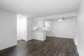 Located at 1750 W Romneya Dr in Anaheim, California, this one-bedroom, one-bathroom unit offers a functional and well-organized single-floor layout. The living room is bright and open, featuring wood-style plank flooring, a textured ceiling, and a large sliding glass door fitted with vertical blinds that allow ample natural light to filter in. A wall-mounted HVAC unit provides dedicated climate control. The kitchen is efficiently designed in a galley-style configuration, offering generous white cabinetry with black hardware, light stone-look countertops, a stainless steel sink, and white appliances including a range and dishwasher. A peninsula counter with seating space connects the kitchen to the living area, enhancing the open feel. The spacious bedroom features plush carpet flooring, crisp white walls, and a window with blinds that brings in natural light. A hallway leads from the bedroom to the bathroom, which includes a white vanity with a mirror, wood-style flooring, and a full tub and shower combo. Throughout the unit, the clean, neutral palette and consistent finishes create a cohesive and move-in-ready atmosphere.