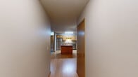 This single-floor residence offers a thoughtfully designed layout encompassing two bedrooms, two bathrooms, and a dedicated laundry room. The kitchen serves as a central highlight, featuring warm honey-toned oak cabinetry, granite-style countertops, stainless steel appliances including a refrigerator, electric range, and built-in microwave, and a central island that provides additional prep and dining space. Light wood-style flooring runs throughout the kitchen and hallway, lending the space a clean, cohesive feel. The living room impresses with vaulted ceilings, plush carpeting, a corner fireplace with a wood-trimmed mantle, and a large window paired with a patio door that invites natural light. Both bedrooms are carpeted and generously sized, with the primary bedroom offering a notably spacious footprint. Each bedroom features windows with wood-trimmed blinds. The two bathrooms are finished with oak vanities, granite-style countertops, and tile flooring. A dedicated in-unit laundry room includes a full-size washer and dryer with overhead oak cabinetry for added storage. Textured ceilings and warm wood trim are consistent throughout, contributing to a comfortable and cohesive aesthetic across the entire residence.