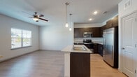 Located at 950 FM-2001 in Buda, TX, this single-floor unit offers a well-designed, open-concept layout with modern finishes throughout. The kitchen serves as the centerpiece of the living space, boasting a large island with a granite countertop and undermount sink, dark espresso cabinetry, and a full suite of stainless steel appliances including a gas range, built-in microwave, and French door refrigerator. Pendant lighting above the island adds a contemporary touch, while light wood-style flooring flows through the kitchen and living areas, enhancing the bright, cohesive feel of the space. Ceiling fans are installed in both the living area and bedrooms for added comfort. The living area is open and airy, with natural light filtering in through windows. The bedrooms feature plush carpeting and generous proportions, with at least one bedroom offering a walk-in closet with built-in shelving. The bathrooms are finished with matching espresso cabinetry, granite-topped vanities, and light wood-style flooring. One bathroom includes a glass-enclosed walk-in shower, while another features a full soaking tub with tiled surround. The unit presents a clean, modern aesthetic throughout.