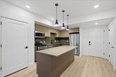 This contemporary apartment showcases a thoughtful blend of modern design and functionality. The open-concept layout is accentuated by large windows that flood the space with natural light, creating an airy and expansive atmosphere. Light wood flooring runs throughout, adding warmth and continuity to the design.

The kitchen is a standout feature, boasting sleek cabinetry in light wood tones, complemented by stainless steel appliances and a spacious island. The clean lines and neutral color palette contribute to the overall modern aesthetic.

The living areas are versatile and well-proportioned, with recessed lighting and minimalist fixtures enhancing the sense of space. The bathroom continues the modern theme with a white color scheme, featuring a bathtub-shower combination and simple, elegant fixtures.

Bedrooms are bright and inviting, with ample closet space. The large windows not only provide natural light but also offer views of the surrounding urban landscape, connecting the interior to the city beyond.

Overall, this apartment exemplifies contemporary urban living, with its emphasis on clean lines, open spaces, and a harmonious blend of form and function.