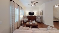 This single-floor residence offers a thoughtfully designed layout with a cohesive aesthetic defined by warm hardwood flooring, neutral wall tones, and crown molding throughout. The living room is a welcoming, light-filled space featuring large windows with decorative drapery, a ceiling fan, and direct access to an exterior door, creating an open and airy atmosphere.

Adjacent to the living area, the formal dining space is anchored by a chandelier and flows naturally from the entryway. The kitchen is a standout feature, showcasing dark espresso cabinetry, granite countertops, stainless steel appliances, and a peninsula island with pendant lighting — offering both style and functionality.

The bedrooms provide comfortable retreats; the primary bedroom includes a ceiling fan and direct access to an en-suite bathroom and a secondary room suitable as a flex space or den, complete with a walk-in closet. The bathroom is well-appointed with a granite vanity, a tile-surround walk-in shower with glass enclosure, and convenient access to an in-unit laundry area housing a full-size washer and dryer.