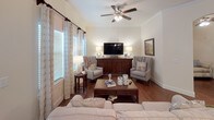 This single-floor residence offers a thoughtfully designed layout with a cohesive aesthetic defined by warm hardwood flooring, neutral wall tones, and crown molding throughout. The living room is a welcoming, light-filled space featuring large windows with decorative drapery, a ceiling fan, and direct access to an exterior door, creating an open and airy atmosphere.

Adjacent to the living area, the formal dining space is anchored by a chandelier and flows naturally from the entryway. The kitchen is a standout feature, showcasing dark espresso cabinetry, granite countertops, stainless steel appliances, and a peninsula island with pendant lighting — offering both style and functionality.

The bedrooms provide comfortable retreats; the primary bedroom includes a ceiling fan and direct access to an en-suite bathroom and a secondary room suitable as a flex space or den, complete with a walk-in closet. The bathroom is well-appointed with a granite vanity, a tile-surround walk-in shower with glass enclosure, and convenient access to an in-unit laundry area housing a full-size washer and dryer.