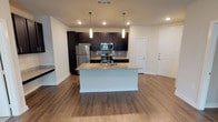 Located at 329 Noel Dr in McKinney, TX, this single-floor residence offers a thoughtfully designed open-concept layout that seamlessly connects the kitchen and living areas. The kitchen is a standout feature, showcasing rich dark espresso cabinetry, granite countertops, a subway tile backsplash, and a full suite of stainless steel appliances including a refrigerator, range, and over-the-range microwave. A central island with pendant lighting provides additional prep space and serves as a natural gathering point. Wood-look plank flooring extends throughout the main living areas, adding warmth and continuity to the open floor plan. The spacious living area is bright and versatile, with a clean, neutral color palette and recessed lighting. The bedroom features plush carpet, a ceiling fan, and a large window that floods the room with natural light. The bathrooms are finished with the same dark cabinetry and granite vanity tops found in the kitchen, ensuring a cohesive aesthetic throughout. One bathroom offers a tiled tub-shower combination, while the other features wood-look flooring and a large mirror above the vanity. Together, the finishes and open layout create a contemporary, move-in-ready living environment.