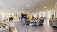 The Residences at Potomac Crest clubhouse is a thoughtfully designed, single-floor community amenity building that offers a welcoming and functional environment for its residents. The entry foyer greets visitors with herringbone-patterned tile flooring, crown molding, and glass double doors that open to an outdoor patio, flooding the space with natural light.

The expansive main lounge serves as the heart of the clubhouse, featuring the same distinctive herringbone tile, recessed lighting, and elevated ceilings with crown molding throughout. Comfortable seating arrangements anchored by area rugs create an inviting atmosphere, while a built-in media center with a large flat-screen TV provides a focal point for gatherings. Glass-paned French doors lead to a private office or workstation area, offering a quiet retreat within the open layout.

The conference room is a polished, dedicated meeting space appointed with a large rectangular table, ergonomic mesh chairs, carpeted floors, and natural light from a window overlooking greenery. Decorative wall art and metallic accents lend a refined, professional tone.

The well-equipped kitchen features rich dark cabinetry, white countertops, stainless steel appliances, a coffee station, and a breakfast bar with upholstered seating — ideal for community events and casual gatherings. A secondary prep kitchen provides additional counter space and storage, completing this versatile and elegantly appointed clubhouse.