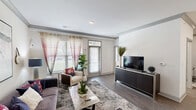 Located at 12601 Charles Farm Cir in Louisville, KY, this single-floor, 2-bedroom, 2-bathroom residence offers a thoughtfully designed open-concept layout. The living room welcomes abundant natural light through large windows dressed with sheer curtains, complemented by wood-look flooring and direct access to an outdoor area via a glass door. The kitchen is a standout feature, boasting dark cabinetry, stainless steel appliances, a white quartz waterfall island with bar seating, and elegant pendant lighting — all flowing seamlessly into the dining area, which offers a cozy space accented by geometric wall shelving. The primary bedroom is a comfortable retreat with walk-in closet access and natural light from windows with blinds. The second bedroom similarly features natural light and ample space. Both bathrooms are finished with dark vanity cabinetry, white countertops, and wood-look tile flooring; one includes a soaking tub and shower combination. A dedicated in-unit laundry room houses a full-size washer and dryer with overhead shelving for added storage. Crown molding details and a neutral color palette throughout lend the home a clean, modern aesthetic.