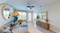 Located at 4741 Hoffner Avenue in Orlando, FL, this well-appointed 2-bedroom, 3-bathroom residence offers a thoughtfully designed single-floor layout with a clean, modern aesthetic and coastal-inspired color palette. Light wood-look flooring flows consistently throughout, unifying the open-concept living spaces.

The kitchen is a standout feature, showcasing flat-panel light wood cabinetry, white quartz countertops, a decorative tile backsplash, stainless steel appliances, and a central island with bar seating — ideal for both cooking and entertaining. The adjacent living room is bright and welcoming, with large windows that invite natural light and offer outdoor views, complemented by a ceiling fan overhead.

Both bedrooms are comfortably sized, with the primary bedroom featuring a soft accent wall, generous closet space, and an en-suite bathroom equipped with a glass-enclosed shower, built-in open shelving, and a wood-toned vanity with a white countertop. The second bedroom also benefits from natural light through large windows. Two dedicated closets provide additional storage throughout the home.

The bathrooms carry the same refined design language — light wood vanities, white countertops, and matte black fixtures — maintaining a cohesive and contemporary feel. Overall, the space exudes a bright, relaxed ambiance with modern detailing at every turn.