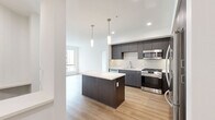 This thoughtfully designed two-bedroom, two-bathroom residence in San Diego, CA offers a clean, modern aesthetic across a single floor. The open-concept kitchen and living area serves as the heart of the home, featuring light hardwood-style flooring, recessed lighting, and a central island with pendant lights overhead. The kitchen is equipped with dark cabinetry, white quartz countertops, stainless steel appliances including a gas range, microwave, and French door refrigerator, complemented by a white tile backsplash.

The living area extends toward large windows and a private balcony door, filling the space with natural light and views of the surrounding community. Both bedrooms are carpeted and well-sized, with the primary bedroom offering a spacious walk-in closet featuring built-in shelving and hanging rods. The primary bathroom includes a dual-sink vanity with dark wood cabinetry, a large mirror, and light hardwood-style flooring. The second bathroom features a full tub/shower combo, a wall-mounted cabinet, and matching light flooring. A hallway connects all rooms, providing a logical and efficient flow throughout this contemporary San Diego residence.