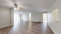 This well-designed three-bedroom, three-bathroom residence in Lakewood, Ohio offers a comfortable and functional single-floor layout. The expansive combined kitchen and living area serves as the heart of the home, featuring durable wood-look plank flooring, neutral-toned walls, and a textured ceiling with a ceiling fan overhead. Large floor-to-ceiling windows and a sliding glass door flood the living space with natural light and provide access to an outdoor balcony area. The kitchen is outfitted with crisp white cabinetry, a classic subway tile backsplash, white appliances including a range, dishwasher, and built-in microwave, complemented by a stainless steel sink. The three bedrooms are carpeted for comfort, with the generously sized primary bedroom offering a dedicated walk-in closet complete with wire shelving and built-in storage. Additional bedrooms also feature closet space. The three bathrooms include tiled tub-shower combinations with clean, classic finishes. A hallway with louvered closet doors provides convenient additional storage. The overall ambiance is clean, bright, and move-in ready, offering a practical and welcoming living environment in a well-established Lakewood location.
