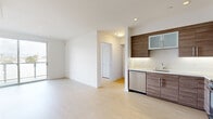 This thoughtfully designed 2-bedroom, 2-bathroom residence offers a clean, contemporary aesthetic throughout its single-floor layout. The open-concept kitchen and living area serves as the heart of the home, featuring light hardwood-style flooring that flows seamlessly through the space. The kitchen is equipped with stainless steel appliances—including a gas range, over-the-range microwave, dishwasher, and refrigerator—complemented by rich wood-toned cabinetry, white quartz countertops, and a clean tile backsplash that together create a modern and functional cooking environment.

The primary bedroom is generously proportioned and benefits from a sliding glass door that opens to a private balcony, inviting natural light and outdoor views. The second bedroom is well-sized with light-filled, neutral walls and hardwood-style flooring consistent with the rest of the unit. A dedicated closet provides additional storage convenience.

Both bathrooms maintain a cohesive modern style, each featuring a tub-shower combination enclosed by sliding glass doors, white tile surrounds with subtle accent banding, wood-toned vanity cabinetry, white countertops, and large-format tile flooring. The overall ambiance of the residence is bright, clean, and minimalist, making it a highly functional and visually appealing living space.