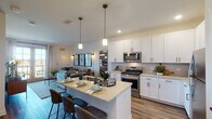 Located on Woodmoor Drive in Lombard, Illinois, this single-floor residence offers a thoughtfully designed open-concept layout with contemporary finishes throughout. The kitchen serves as the centerpiece of the main living area, showcasing crisp white cabinetry with matte black hardware, granite-look countertops, and a full suite of stainless steel appliances including a gas range, over-the-range microwave, and refrigerator. A central island with seating provides both additional workspace and a casual dining option, while pendant lighting adds a warm, modern touch overhead. Wood-look flooring flows throughout the main living areas, grounding the open design.

The living area connects seamlessly to the kitchen and features French doors that open to a private balcony, offering outdoor views and abundant natural light. The bedroom is a comfortable retreat with plush carpeting, large windows overlooking the surrounding landscape, and ample closet space. The bathroom is well-appointed with a granite-topped vanity, white cabinetry, and a full tub-shower combination. Neutral tones and clean lines carry throughout the residence, creating a cohesive and inviting atmosphere suited for everyday living.