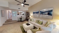 This well-appointed 3-bedroom, 2-bathroom single-story residence offers a thoughtfully designed layout that maximizes comfort and functionality. The open-concept living area immediately impresses with its vaulted ceilings and a ceiling fan that enhances the sense of airiness. Plush carpeting and warm, neutral tones throughout create a welcoming ambiance. Large windows allow natural light to fill the space, further brightening the interior.

The living room provides generous space for seating and relaxation, flowing naturally into the dining area, which is illuminated by a pendant light fixture and framed by a pass-through that connects to the kitchen. The kitchen features ample cabinetry and counter space, making it both practical and accessible.

The primary bedroom suite is a comfortable retreat, offering ample room and access to a full bathroom. Two additional bedrooms provide flexible space suitable for guests, a home office, or family use, complemented by a second full bathroom conveniently located nearby.

A dedicated laundry area adds everyday convenience, while the overall floor plan ensures a smooth and logical flow between all living spaces. The combination of vaulted ceilings, open sightlines, and warm finishes gives this home a distinct sense of space and livability throughout.