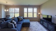 This thoughtfully designed single-floor residence offers a functional and comfortable layout across a variety of well-appointed spaces. The kitchen serves as a central highlight, featuring white cabinetry, dark granite countertops, a tile backsplash, and a full suite of stainless steel appliances including a gas range, microwave, and French door refrigerator. A breakfast bar with seating connects the kitchen to the rest of the living area, enhancing the open feel of the space. The dining area is filled with natural light from large windows and a sliding glass door that opens to the outdoors, offering pleasant views of a green landscape. A modern globe pendant light adds a stylish focal point overhead. The living room continues the bright, airy atmosphere with a wide bank of windows framing outdoor views and dark hardwood-style flooring that flows throughout the space. Two well-sized bedrooms each feature natural light from large windows, dark wood flooring, and closet space. Both full bathrooms are finished with tile surrounds on the tub-shower combinations, updated vanities, and neutral toned walls. The in-unit laundry room provides added convenience with a full-size washer and dryer and durable tile flooring, completing this practical and inviting residence.