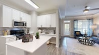 Located in Atlanta, GA, this single-floor, 2-bedroom, 2-bathroom residence offers a thoughtfully designed layout with modern finishes throughout. The kitchen is a standout feature, boasting white shaker cabinetry, a textured tile backsplash, quartz countertops, stainless steel appliances, and a central island that flows seamlessly into the adjoining dining area. Crown molding and hardwood-style flooring add a polished touch to the main living spaces. The living room impresses with a tray ceiling, ceiling fan, and large windows that invite abundant natural light and outdoor views. The primary bedroom offers plush carpeting, a ceiling fan, and a spacious walk-in closet with built-in shelving. The second bedroom also features large windows with greenery views, providing a bright and comfortable retreat. Both bathrooms are finished with white cabinetry, clean tile work, and tub-shower combinations. A dedicated in-unit laundry room with washer and dryer adds everyday convenience. The neutral, warm color palette carried throughout creates a cohesive and inviting ambiance, making this residence a comfortable and functional home in the Northlake area of Atlanta.