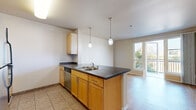 Located in San Diego's vibrant East Village neighborhood, this one-bedroom, one-bathroom residence offers a well-designed layout across a single floor. The open-concept kitchen and living area form the heart of the home, featuring warm honey-toned cabinetry, dark countertops, a double-basin sink, stainless steel appliances including a refrigerator, microwave, and dishwasher, and tile flooring. Pendant lighting above the kitchen peninsula adds a polished touch while defining the space. The living area transitions seamlessly from the kitchen and is finished with light hardwood-style flooring that continues throughout the unit, lending warmth and visual continuity. Large floor-to-ceiling windows and a glass-paneled door open directly onto a private balcony, filling the space with abundant natural light and offering views of the surrounding San Diego cityscape. The bedroom is a comfortable, well-proportioned room with a large window fitted with vertical blinds, providing ample light and outdoor views. The bathroom echoes the design aesthetic of the kitchen, with matching cabinetry, dark countertops, a large vanity mirror, and tile flooring. Clean, neutral wall tones throughout create a cohesive and move-in-ready atmosphere.