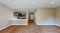 This two-story home offers a thoughtfully designed layout spread across two floors, providing comfortable living for everyday life. The main floor features an open-concept kitchen and living area, where the kitchen stands out with rich dark-stained cabinetry, white quartz countertops, stainless steel appliances including a refrigerator, range, microwave, and dishwasher, and stylish pendant lighting over the peninsula. Warm hardwood-style flooring anchors the kitchen, while the adjacent living space flows seamlessly with carpeted flooring and access to the outdoors through sliding glass doors that invite natural light and outdoor views.

Upstairs, the generously sized primary bedroom offers plush carpeting, a ceiling fan, and ample space to relax. The additional bedrooms are equally well-sized, each with soft carpet and neutral wall tones. All three bathrooms are finished with wood-toned vanity cabinets, white countertops, and matte black fixtures, lending a modern yet understated aesthetic throughout. A dedicated closet provides practical storage, while two staircases ensure convenient access between levels. The home's consistent use of warm neutral tones, modern hardware, and quality finishes creates a cohesive and inviting atmosphere from top to bottom.