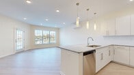 Located at 22 Summit Pl in Branford, CT, this thoughtfully designed 2-bedroom, 2-bathroom residence offers a bright, modern living experience on a single floor. The open-concept living, dining, and kitchen area serves as the heart of the home, where light-toned luxury vinyl plank flooring flows seamlessly throughout. The kitchen is well-equipped with crisp white cabinetry, granite countertops, a subway tile backsplash, and a full suite of stainless steel appliances, including a refrigerator, range, microwave, and dishwasher. A central island with pendant lighting adds both function and style, while large windows bathe the adjacent living and dining area in natural light. The primary bedroom is generously sized and features windows with outdoor views and a wall-mounted mini-split climate control unit. The second bedroom and additional den offer flexible space for guests or a home office, each with their own mini-split units. Both bathrooms are finished with neutral tile flooring and modern vanities; the primary bath includes a clean, walk-in tiled shower. Four closets provide ample storage throughout. Recessed lighting, clean neutral walls, and a cohesive contemporary palette give the entire residence a polished, move-in-ready feel.