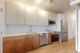 This one-bedroom, one-bathroom residence at 1100 Dahlia St NW in Washington, DC offers a well-designed layout with modern finishes throughout. Light hardwood flooring flows seamlessly across the entire unit, creating a bright and cohesive aesthetic.

The open-concept living and dining area connects directly to the kitchen, which is outfitted with stainless steel appliances — including a refrigerator, range, dishwasher, and microwave — paired with two-tone cabinetry featuring warm wood lower cabinets and crisp white uppers. A subway tile backsplash and clean countertops complete the contemporary look. A distinctive frosted-glass sliding barn door adds a stylish, functional element between the living space and kitchen area.

The hallway leads to the bedroom, which features sliding glass doors opening onto a private balcony with outdoor views. The bedroom also includes a dedicated closet for storage. The full bathroom offers a tiled tub-shower combination with clean, white finishes.

Additional highlights include an in-unit laundry area and track lighting in the main living and kitchen spaces. The unit's clean, neutral palette and modern design details make it a functional and stylish home in the Takoma neighborhood of Washington, DC.
