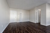 Located at 625 N Sycamore Ave in the heart of Hollywood, Los Angeles, this single-floor unit offers a clean, modern interior with a practical and well-organized layout. Rich dark hardwood-style flooring runs throughout the main living areas, creating a warm contrast against the neutral beige walls and white trim. The open living area is bright and welcoming, featuring multiple windows with blinds that allow ample natural light to fill the space. A ceiling fan provides additional comfort, and a wall-mounted air conditioning unit ensures year-round climate control. The textured ceiling adds a classic touch throughout.

The kitchen is efficiently designed with crisp white cabinetry, light stone-look countertops, and stainless steel appliances including a gas range and refrigerator. A window above the counter brings in natural light, making the space feel airy despite its compact footprint. Generous cabinet storage extends into the adjacent area, offering practical organization solutions.

The bathroom is tastefully updated, showcasing a tub and shower combination enclosed by sliding glass doors. White subway tile with decorative blue mosaic accent bands lines the shower walls, adding a stylish detail. The bathroom also features wood-look flooring and a light stone countertop vanity. A solid front entry door with a sidelight window completes this well-maintained, move-in-ready space.
