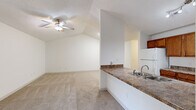 Located at 6230 Abbotts Park Dr in Fayetteville, NC, this single-floor home offers four bedrooms and two full bathrooms across a well-organized layout. The open-concept living area features vaulted ceilings, a ceiling fan with light fixture, and plush carpeting, with a door providing direct access to an outdoor deck. Natural light fills the space through multiple windows fitted with blinds. The kitchen is a functional galley-style space equipped with warm wood cabinetry, granite-look countertops, a double-basin sink, and white appliances including a refrigerator, electric range, microwave, and dishwasher. A peninsula counter with a built-in sink opens toward the living area, ideal for casual dining or entertaining. Each bedroom features carpet flooring and a ceiling fan, with the generously sized primary bedroom offering ample space. The two bathrooms include a wood-vanity with granite-look countertop, light wood-look flooring, and a full tub-shower combination. A dedicated laundry room houses a full-size washer and dryer with overhead shelving for added storage. Throughout the home, neutral tones and clean finishes create a bright, welcoming ambiance.