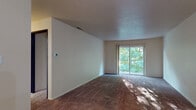 Located at 1305 W Vistula St in Bristol, Indiana, this single-floor residence offers a practical and comfortable layout across several well-defined living spaces. The spacious living area is finished with plush carpeting and features a sliding glass door that floods the room with natural light and provides direct views of the surrounding mature trees. A ceiling fan adds both function and character to the adjoining room, which also connects conveniently to the kitchen. The kitchen is equipped with warm wood cabinetry, white appliances including a range and dishwasher, a single-basin sink, and light-toned countertops, all set atop wood-look flooring. Multiple bedrooms are carpeted and benefit from windows that frame lush, green outdoor scenery, creating a calm and natural ambiance throughout. The bathroom includes a full tub and shower combination with white tile surround, complemented by a separate vanity area featuring a wide countertop, an undermount sink, and a large mirror. The overall design is straightforward and functional, with neutral tones and soft carpeting throughout the main living and sleeping areas, offering a clean canvas well-suited to a variety of living arrangements.