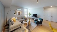 Located at 259 Ferncliff Ave NE on scenic Bainbridge Island, Washington, this thoughtfully designed single-floor residence combines contemporary style with functional living. The open-concept layout connects the living, dining, and kitchen areas seamlessly, creating a welcoming and cohesive atmosphere throughout.

The living area is bright and modern, featuring light hardwood flooring, track lighting, and large windows fitted with blinds that invite abundant natural light. A sectional sofa, accent seating, and layered rugs contribute to a warm, curated aesthetic. A dedicated dining nook accommodates a full table and seating, ideal for everyday meals or entertaining.

The kitchen is outfitted with flat-front wood-grain cabinetry, stainless steel appliances including a French door refrigerator and dishwasher, a tile backsplash, and ample counter and storage space — well-suited for serious cooking.

The primary bedroom is a calm retreat, distinguished by a teal accent wall, plush carpeting, generous windows overlooking lush Pacific Northwest greenery, and a walk-in closet. A secondary room serves flexibly as a home office or additional bedroom, featuring carpet, a large window with tree views, and space for a desk and lounge seating. The overall ambiance is clean, contemporary, and thoughtfully composed throughout.