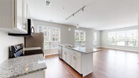 Located at 800 Baldwin Dr. in Grandview Heights, Ohio, this single-floor residence offers a thoughtfully designed open-concept layout filled with natural light and contemporary finishes throughout. Rich hardwood-style flooring runs through the main living areas, creating a warm and cohesive aesthetic.

The kitchen is a standout feature, showcasing granite countertops, crisp white shaker cabinetry, a subway tile backsplash, and a full suite of stainless steel appliances including a refrigerator, range, microwave, and dishwasher. A large center island with a double sink and pendant lighting above serves as a natural gathering point, flowing seamlessly into the open living area. The living room is bright and generously proportioned, with multiple windows offering outdoor views and an abundance of natural light.

A hallway connects the main living space to the private areas of the residence, where a dedicated in-unit laundry closet houses a stacked washer and dryer. The bedroom features plush carpeting and large windows. The bathroom is well-appointed with a wide vanity, white cabinetry, and hardwood-style flooring, accompanied by a spacious walk-in closet with wire shelving for ample storage. Neutral tones throughout create a clean, move-in-ready environment.