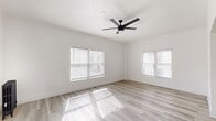 Located at 511 S Serrano Ave in the heart of Los Angeles, CA, this thoughtfully designed single-floor unit offers a clean, modern aesthetic throughout. The sun-drenched living room is a standout feature, boasting multiple windows with blinds that flood the space with natural light, light wood-style flooring, and a sleek black ceiling fan overhead. A charming arched doorway and a classic cast-iron radiator add character to the otherwise contemporary interior. The galley-style kitchen is well-equipped with white shaker cabinets featuring matte black hardware, dark stone countertops, and stainless steel appliances including a gas range, microwave, and full-size refrigerator. The bathroom maintains the home's crisp white palette, complete with a tub, vanity, and a window for natural ventilation. Two closets provide ample built-in storage, including one with sliding doors and upper cabinetry. A dedicated entrance and hallway connect the rooms in a functional layout. The consistent light-toned flooring and bright white walls throughout create a cohesive, airy ambiance that maximizes the sense of space.