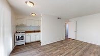 Located at 3827 E Third St in Tucson, Arizona, this single-floor unit offers a straightforward and functional layout suited for everyday living. The main living area is open and well-proportioned, featuring wood-look hardwood-style flooring that extends throughout the space, white painted walls with exposed brick detailing, and a textured ceiling. A large vertical-blind window allows natural light to fill the room, while a sliding glass door provides additional brightness and outdoor access.

The kitchen is efficiently designed and open to the living area, equipped with white cabinetry, a gas range, a double-basin sink with a granite-style countertop, and a range hood. The white brick wall backdrop gives the kitchen a clean, classic character.

The bedroom is a quiet, well-lit room featuring the same wood-look flooring, painted brick walls, and a window with vertical blinds that brings in natural light. The bathroom includes a vanity with a granite-style countertop, an undermount sink, and a large framed mirror, complemented by white brick walls that maintain the consistent aesthetic found throughout the unit.

Central air ventilation is present throughout the space, and the overall design prioritizes clean lines and a neutral palette, creating a versatile and move-in ready environment.