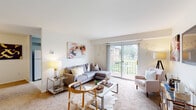 Located in Perry Hall, Maryland, this single-floor residence offers a thoughtfully designed layout that balances comfort and functionality. The living room is bright and welcoming, featuring plush carpeting, neutral walls, and a large sliding glass door that opens to a private balcony with outdoor views of lush greenery — allowing natural light to fill the space throughout the day.

Adjacent to the living room, a dedicated dining area provides an intimate setting for meals, complete with pendant lighting and ample wall space for decorative accents. The kitchen is efficiently arranged with rich dark wood cabinetry, light countertops, a gas range, and a sink, offering practical storage and workspace for everyday cooking.

The primary bedroom is a serene retreat, featuring soft carpeting, generous window placement for natural light, and a calm, neutral color palette. A secondary bedroom provides versatile space, comfortably accommodating twin beds with warm wall sconce lighting and a cozy atmosphere.

Two bathrooms serve the residence: one featuring yellow subway tile wainscoting, a glass-enclosed shower, and a wood-framed vanity mirror, while the second offers a full tub-shower combination, mosaic tile flooring, and clean white finishes. Together, the rooms create a cohesive and comfortable living environment well-suited to Perry Hall's residential character.
