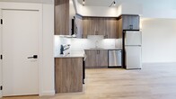 Located at 647 Goldstream Avenue in Langford, BC, this two-storey residence offers a well-designed layout across two floors, combining modern finishes with functional living spaces. The main floor features an open-concept kitchen equipped with wood-grain cabinetry, stainless steel appliances including a range, built-in microwave, dishwasher, and refrigerator, complemented by light quartz countertops and a white tile backsplash. Light hardwood-style flooring flows throughout the main level, enhancing the bright, airy atmosphere. A carpeted staircase connects to the upper floor, where the bedrooms are situated. The primary bedroom benefits from large windows that invite natural light and offer views of surrounding greenery, accented by wall sconces and hardwood-style flooring. The second bedroom is finished with the same light flooring and clean white walls. A dedicated walk-in closet with built-in wire shelving provides generous storage. The two bathrooms are clean and contemporary — one features a glass-enclosed walk-in shower, while the other includes a full soaker tub and shower combination with light wood flooring. The upper level also includes a carpeted room with an open loft-style overlook, adding architectural interest to the overall design.