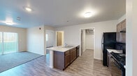 Located at 1410 Catron Blvd in Rapid City, South Dakota, this single-floor, 2-bedroom, 3-bathroom residence offers a practical and well-appointed layout designed for comfortable living. The kitchen serves as a central hub, featuring a peninsula island with an integrated sink and light countertops, dark-stained cabinetry, and black appliances including a gas range, microwave, and refrigerator. Wood-look vinyl plank flooring runs through the kitchen and main living areas, providing a clean, cohesive aesthetic. Both bedrooms are carpeted and receive natural light through window blinds, with the primary bedroom offering a built-in closet with wood-tone sliding doors. A dedicated walk-in closet with wire shelving provides additional storage. The three bathrooms vary in configuration: one features a fully accessible roll-in shower with grab bars and an open-concept vanity, another includes a standard tub-shower combination, and a third offers a streamlined vanity setup. The in-unit laundry room houses a Whirlpool washer and dryer alongside the mechanical equipment. Neutral wall tones and clean white trim carry throughout the space, creating a bright, move-in-ready environment suited for a range of occupants.